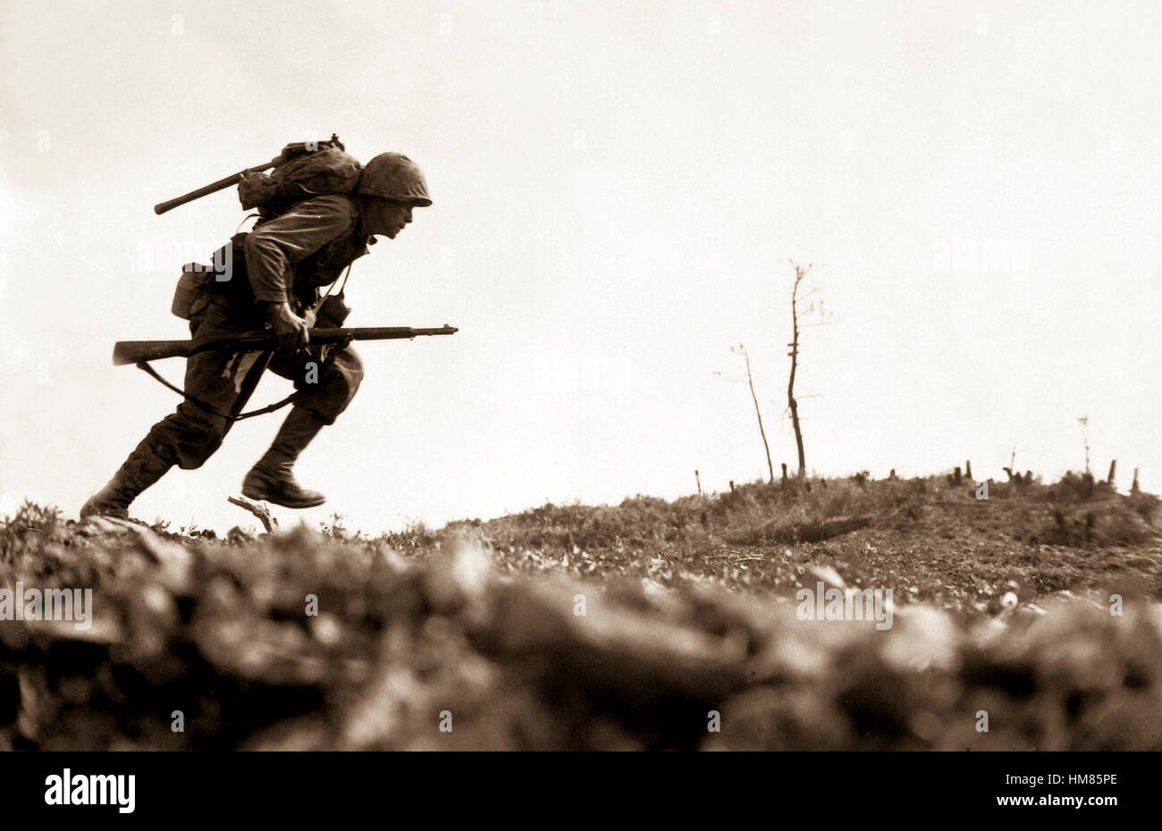 A Marine dashes through Japanese machine gun fire while crossing a draw, called Death Valley by the men fighting there.  Marines sustained more than 125 casualties in eight hours crossing this valley.  Okinawa, May 10, 1945.  Pvt. Bob Bailey.  (Marine Corps) NARA FILE #:  127-N-120562 WAR & CONFLICT BOOK #:  1229 Stock Photo