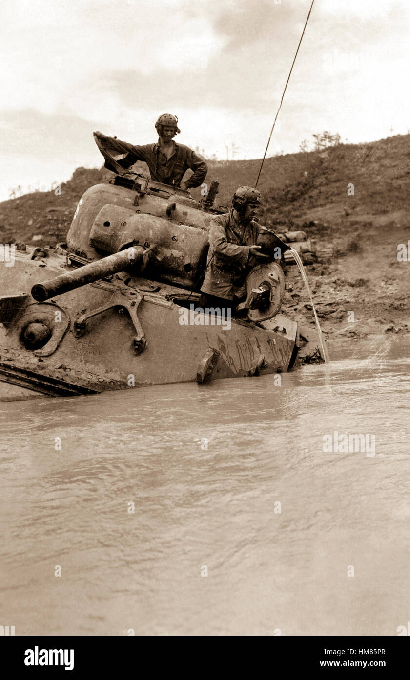 A tank sunk in 5 feet of water waits for towing equipment.  The Tank Commander gives vent to his feelings with a string of unprintable phraseology, while his driver uses a helmet to bale out the interior.  Okinawa, May 1945.  Alexander Roberts. (Army) Exact Date Shot Unknown NARA FILE #:  111-SC-209070 WAR & CONFLICT BOOK #:  1234 Stock Photo