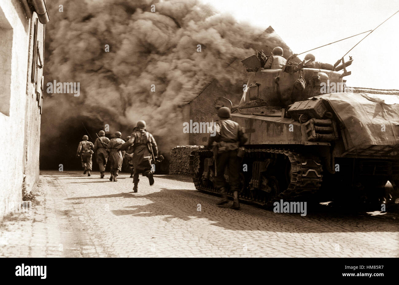 Soldiers of the 55th Armored Infantry Battalion and tank of the 22nd Tank Battalion, move through smoke filled street.  Wernberg, Germany.  April 22, 1945.  Pvt. Joseph Scrippens.  (Army) NARA FILE #:  111-SC-205298 WAR & CONFLICT BOOK #:  1094 Stock Photo