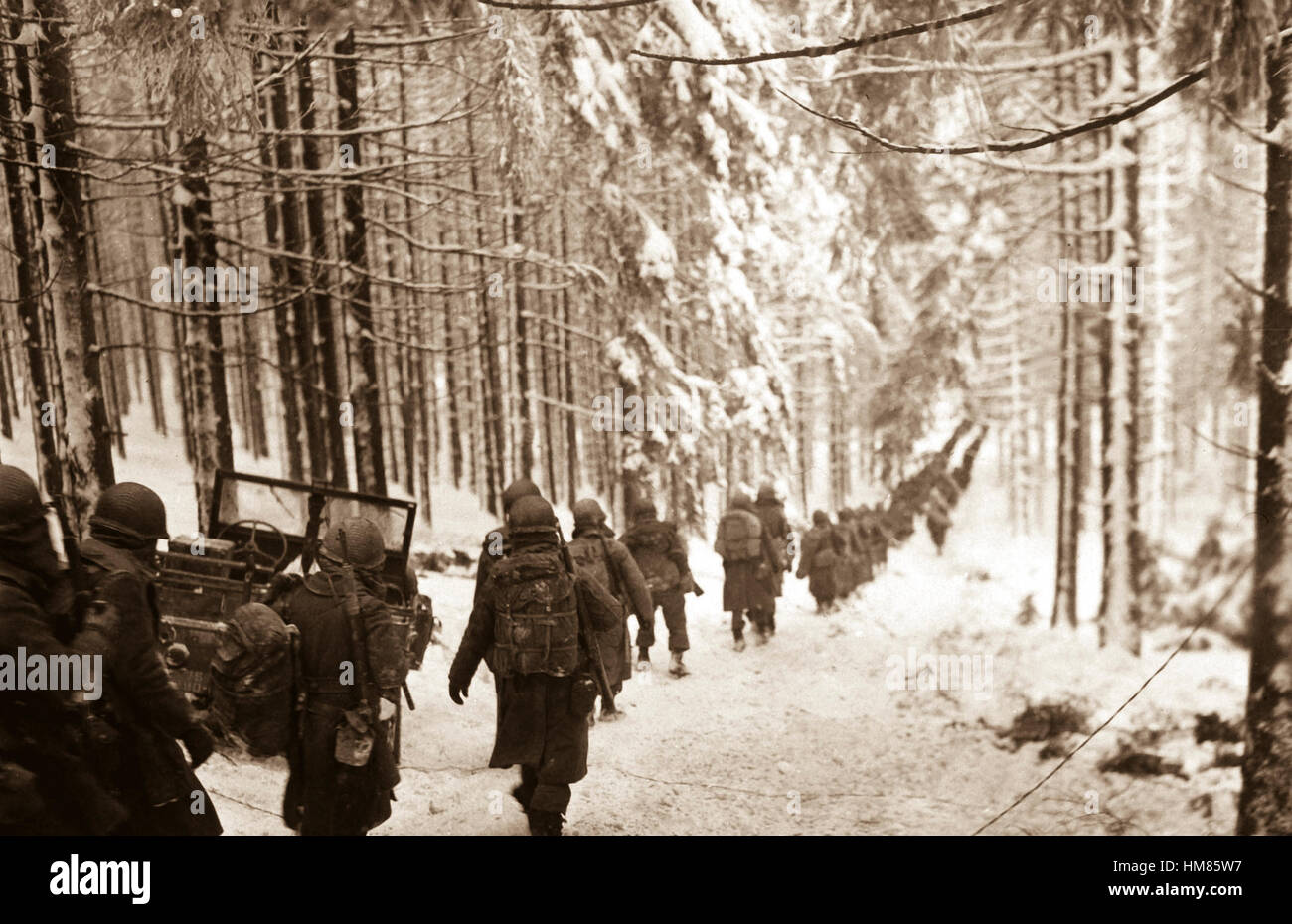 American soldiers of the 289th Infantry Regiment march along the snow-covered road on their way to cut off the St. Vith-Houffalize road in Belgium.  January 24, 1945.  Richard A. Massenge.  (Army) NARA FILE #:  111-SC-199406 WAR & CONFLICT BOOK #:  1079 Stock Photo