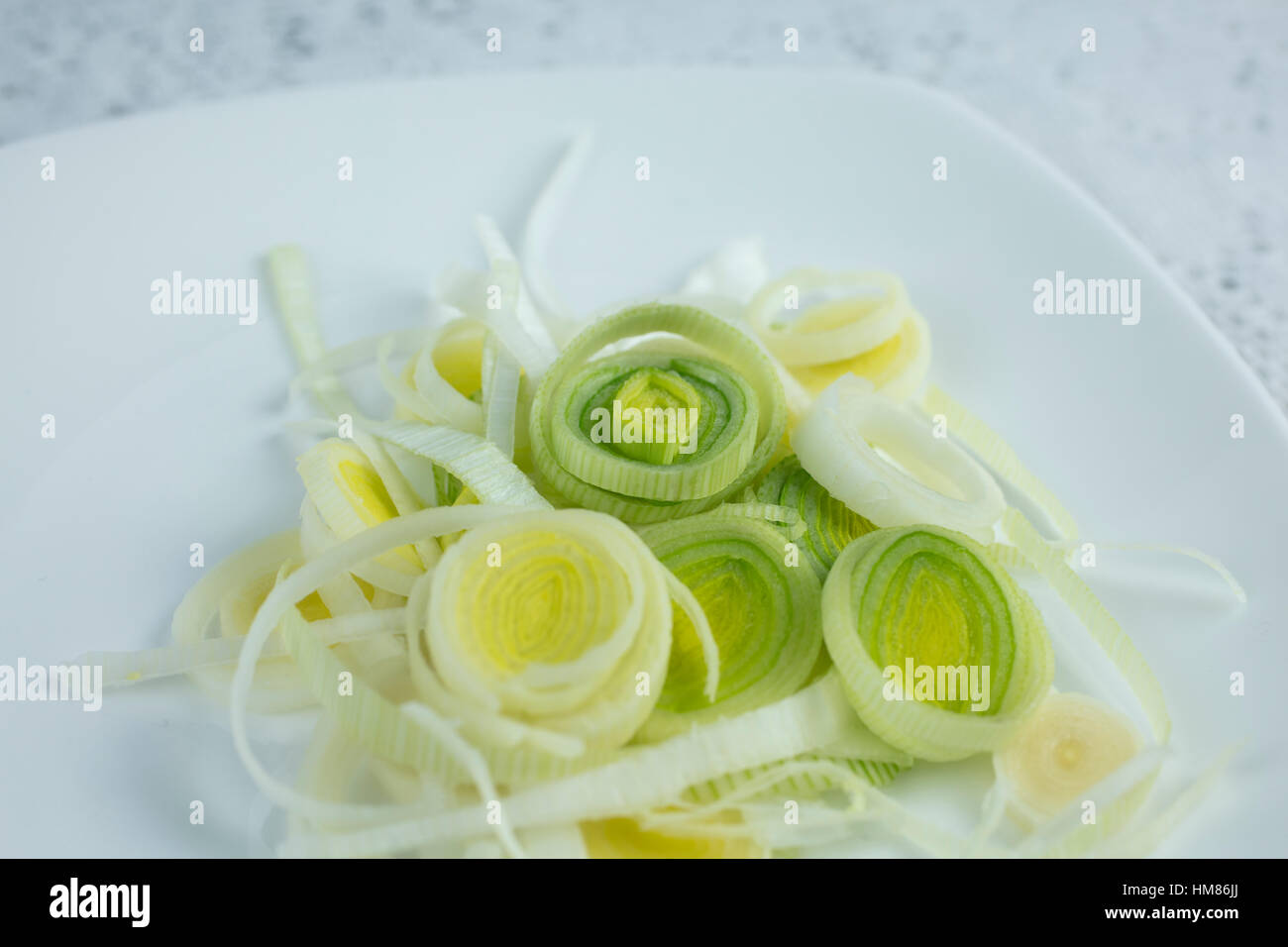 Leeks sliced in thin rings on a white plate to be used for an ...