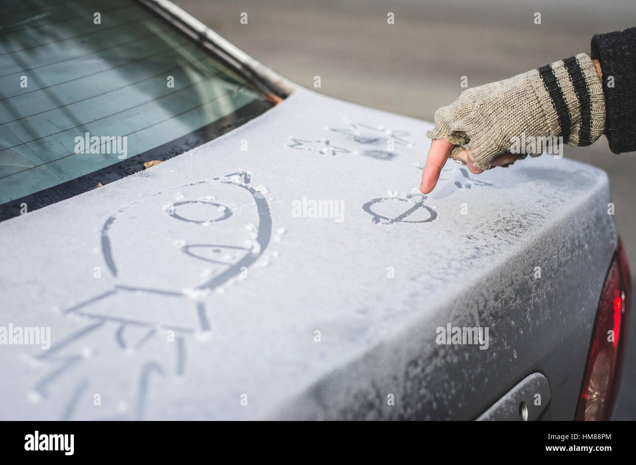 Person Drawing Pictures in Frost on Car Stock Photo