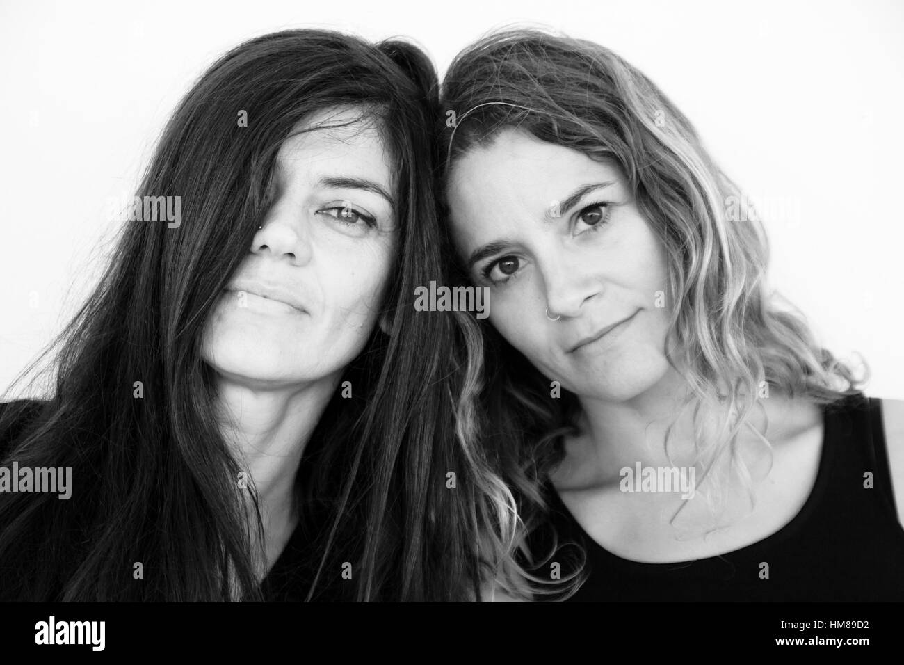 Portrait of Two Adult Women Leaning their Heads Against Each Other Stock Photo