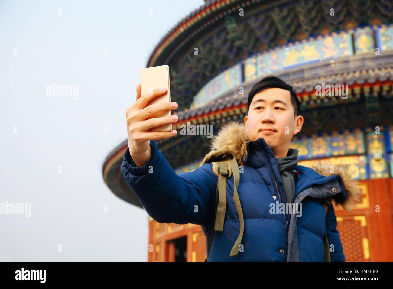 Asian man wearing winter jacket and using a smart phone over Chinese ...
