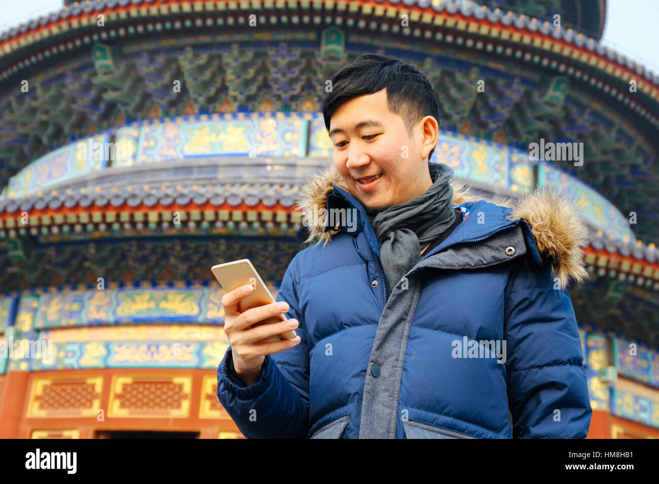 Asian man wearing winter jacket and using a smart phone over Chinese ...