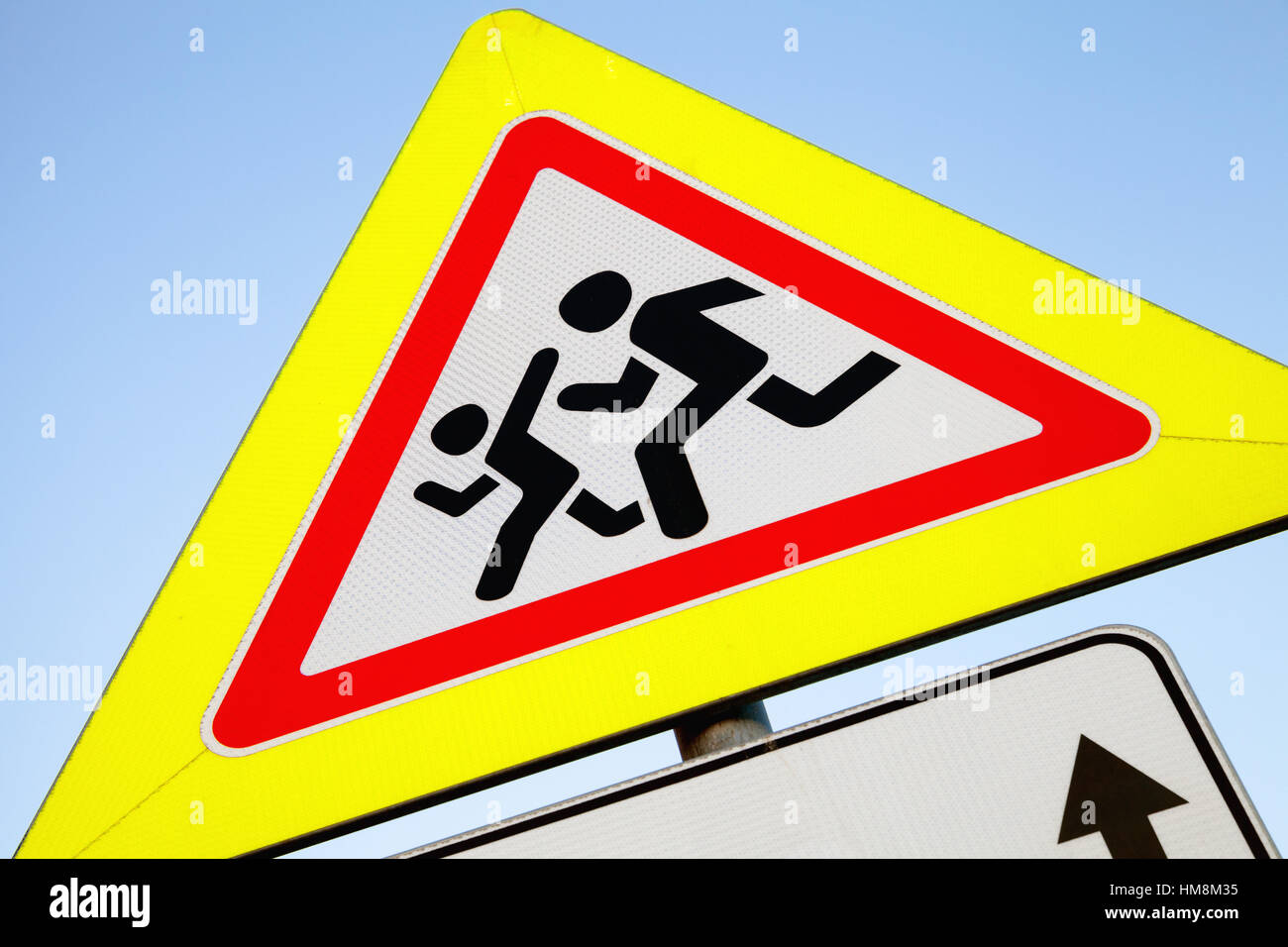 Caution children, Road sign in yellow frame over bright blue sky background Stock Photo
