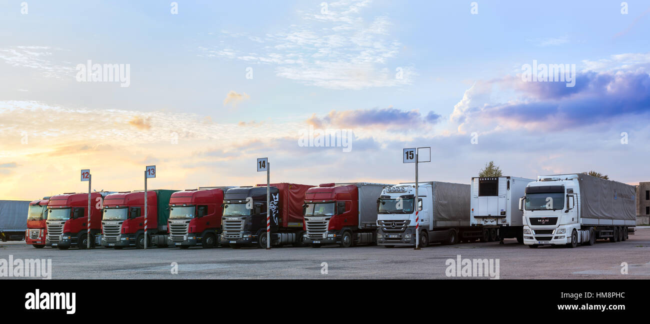 Narva, Estonia - August 20, 2016: Scania, MAN & Mercedes heavy trucks loaded with goods trailers, parked in waiting area on Estonian-Russian state bor Stock Photo