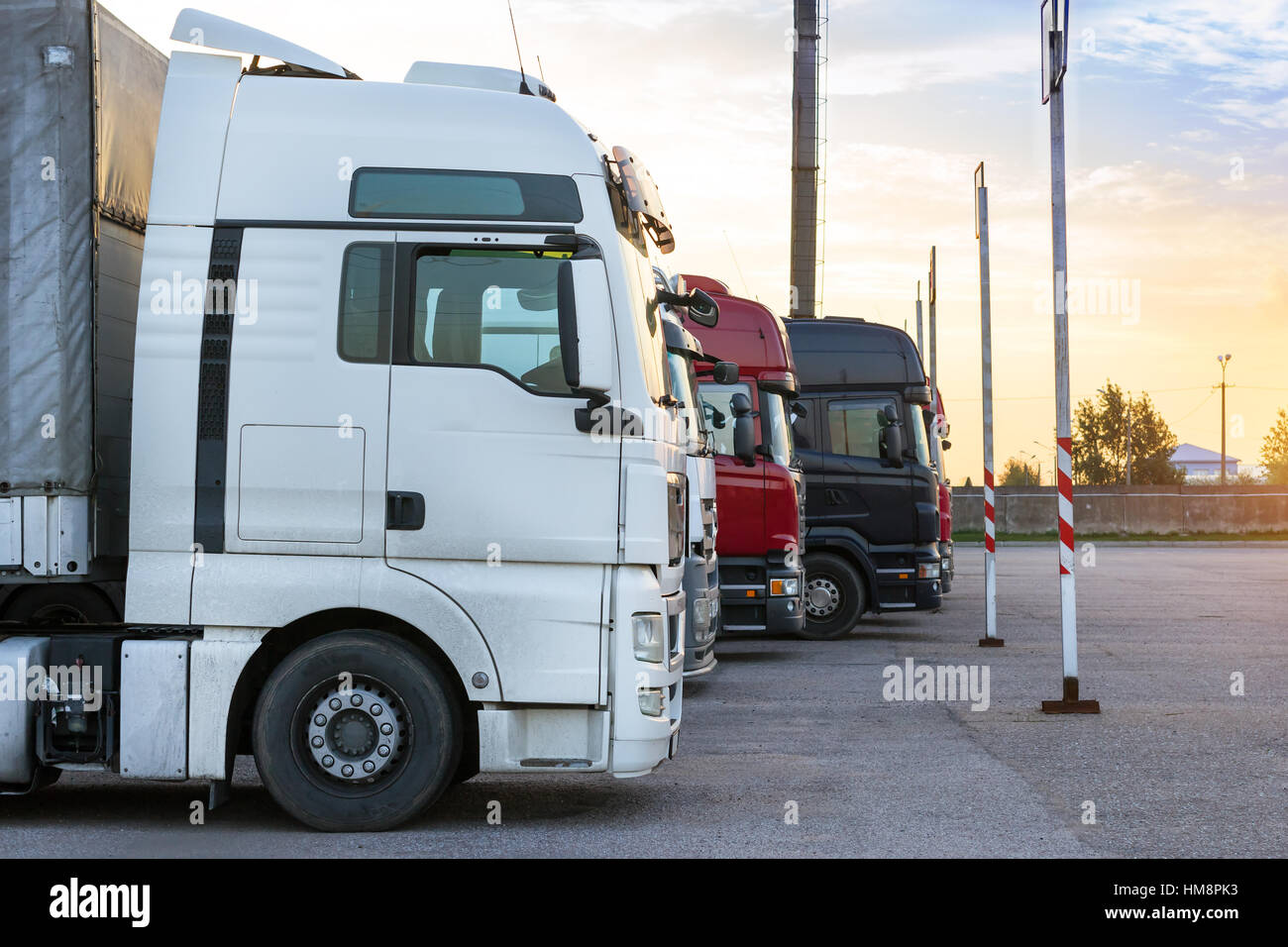 Heavy trucks loaded with goods trailers, parked in waiting area on state border crossing. International hard transportation and logistics. Transport i Stock Photo