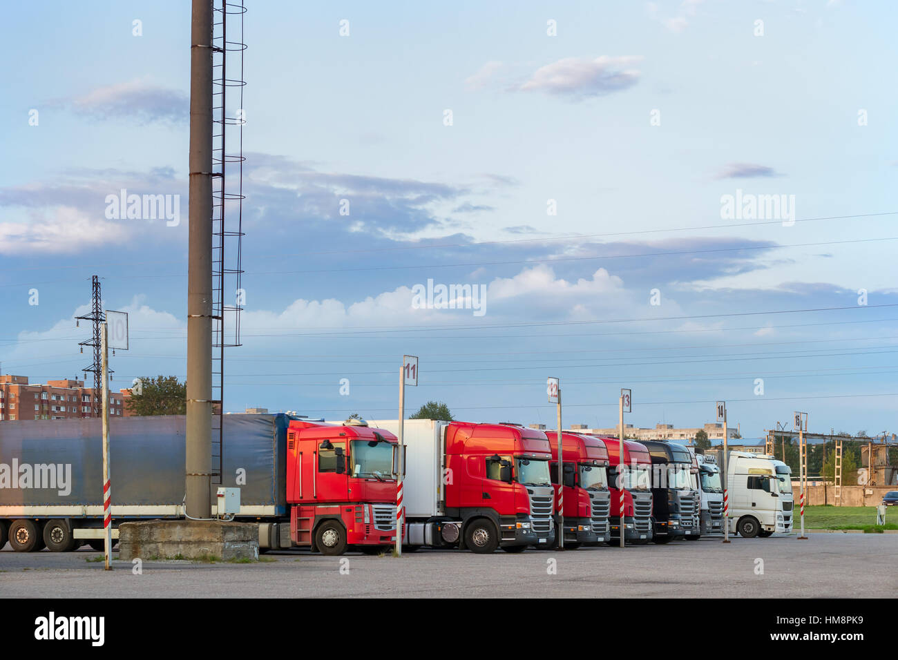 Heavy trucks with trailers loaded with merchandise, stand in a row on an asphalt car platform. International cargo transportation and logistics. Road  Stock Photo