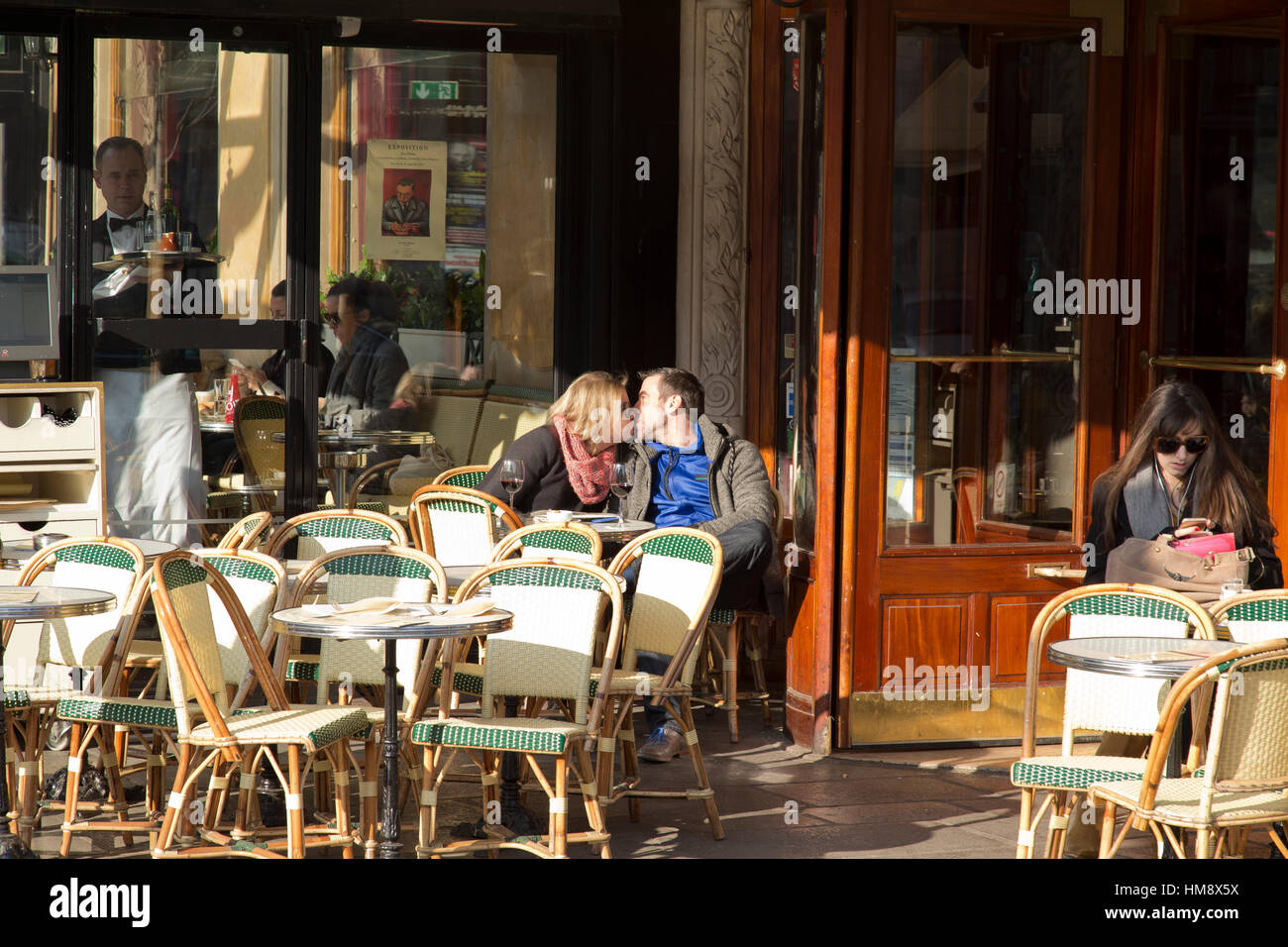 couple kissing outside Les Deux Magots cafe in Paris France in winter Stock Photo