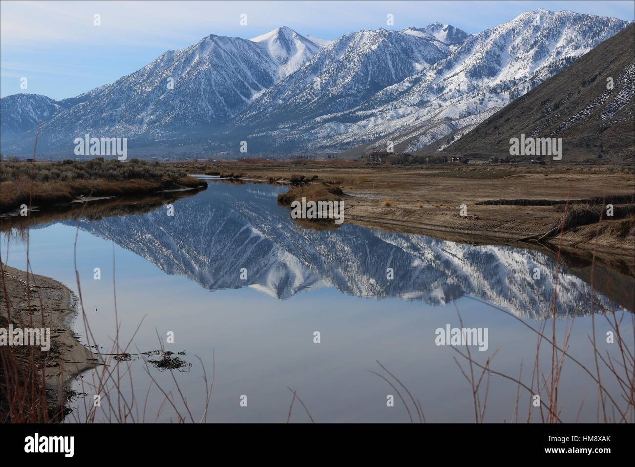 The eastern side of the Sierra Nevada mountains reflect in a pond located in the Carson Valley, near Genoa, Nevada. Stock Photo