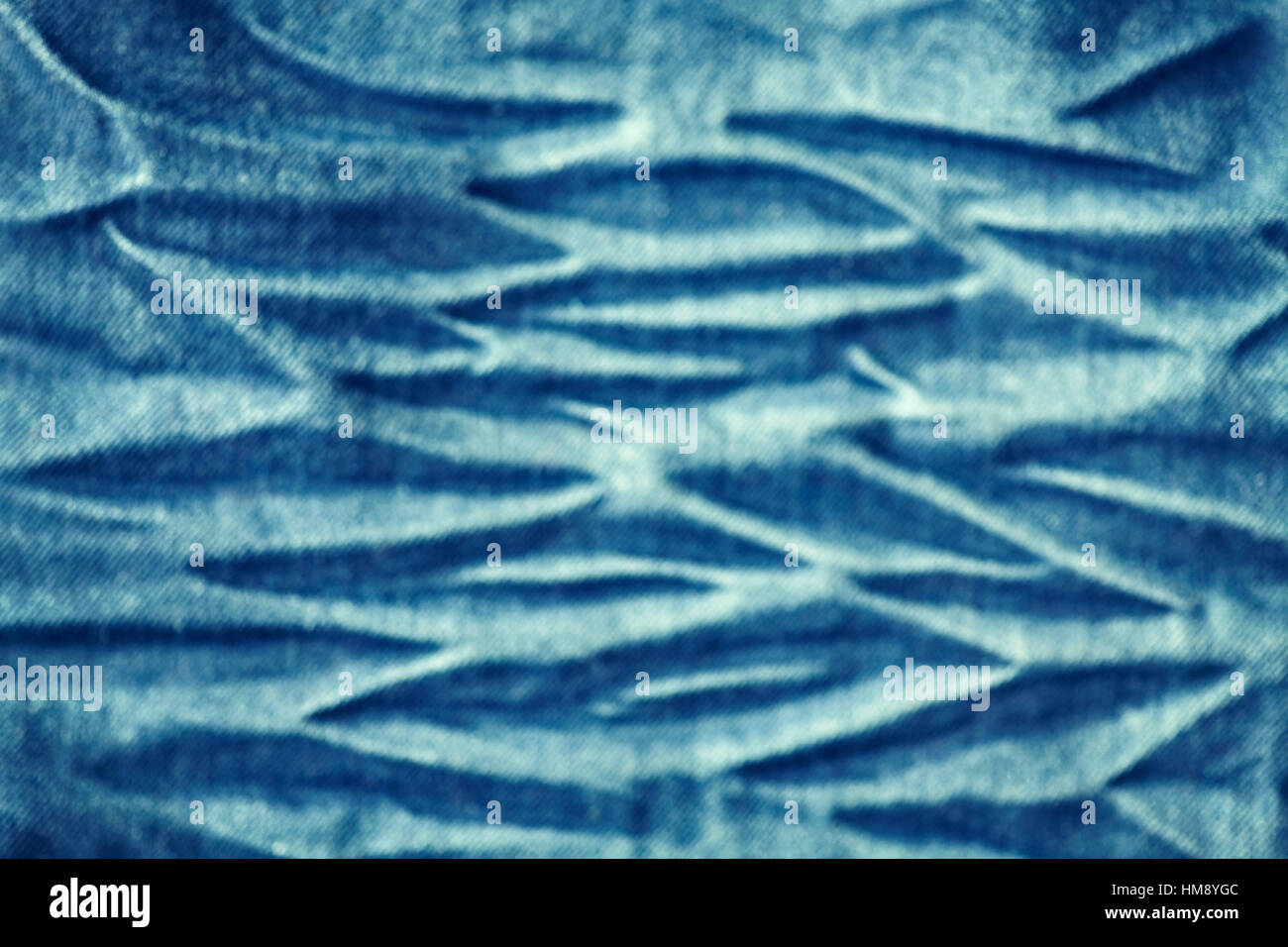 Blurred close up picture of wrinkled jeans fabric, abstract background. Stock Photo