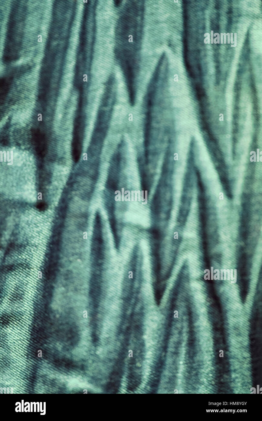 Blurred close up picture of green wrinkled jeans fabric, abstract background. Stock Photo