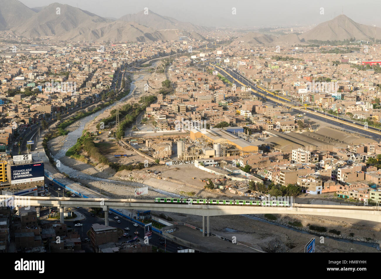View of San Juan de Lurigancho, the most populated district in Lima and in Latin America. At the forefront, train of the 'Metro de Lima' service. Stock Photo