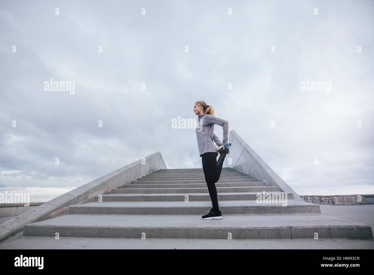 Side view shot of fit young woman stretching legs outdoors. Female exercising in the morning. Stock Photo