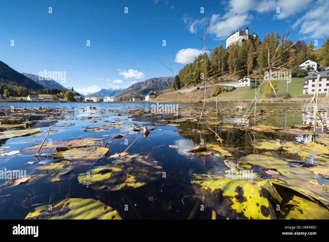 Autumn leaves in Lake Tarasp frame the old castle, Inn district, Canton of Graubunden, Engadine, Switzerland Stock Photo