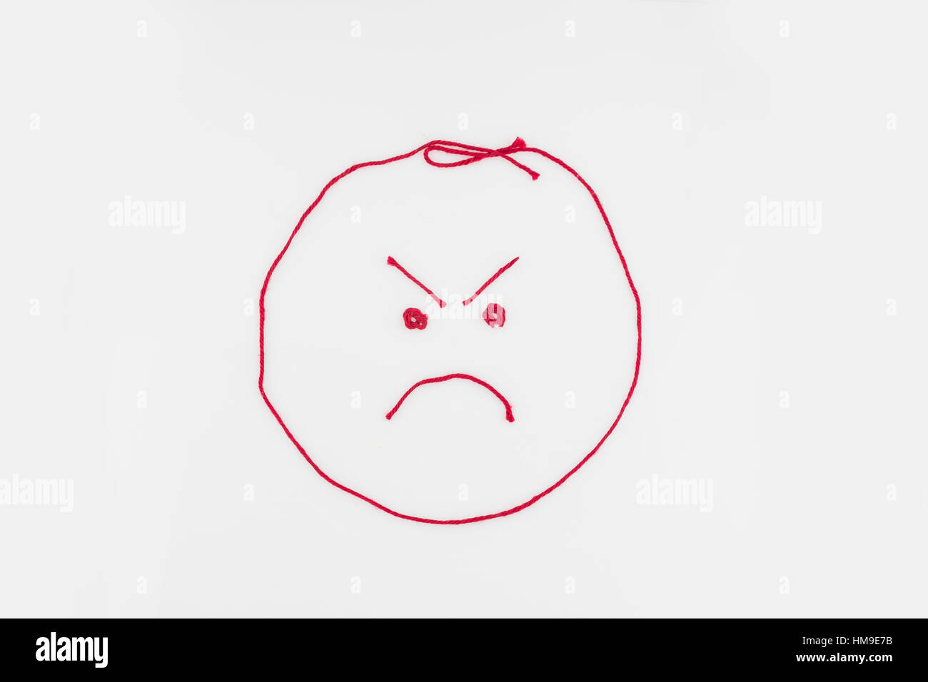 An angry face shaped from red yarn. Cutout. Illustration. Concept, conceptual. Stock Photo