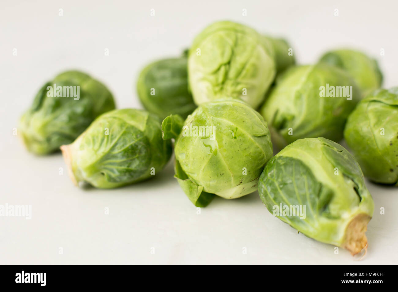 a close-up angle on a pile of organic brussels sprouts on a white table Stock Photo