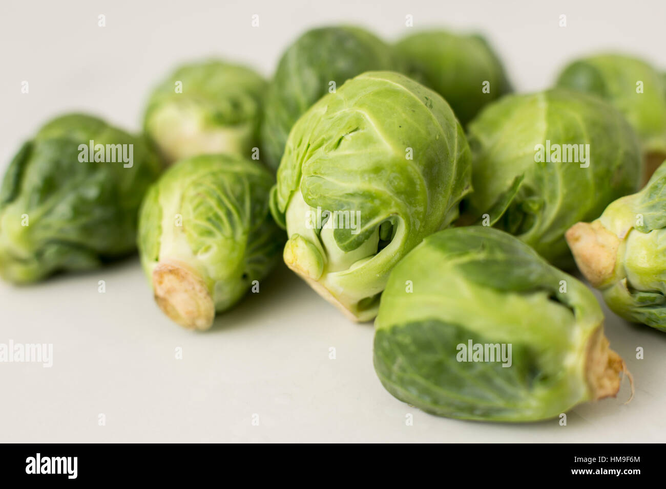 a close-up angle on a pile of organic brussels sprouts on a white table Stock Photo
