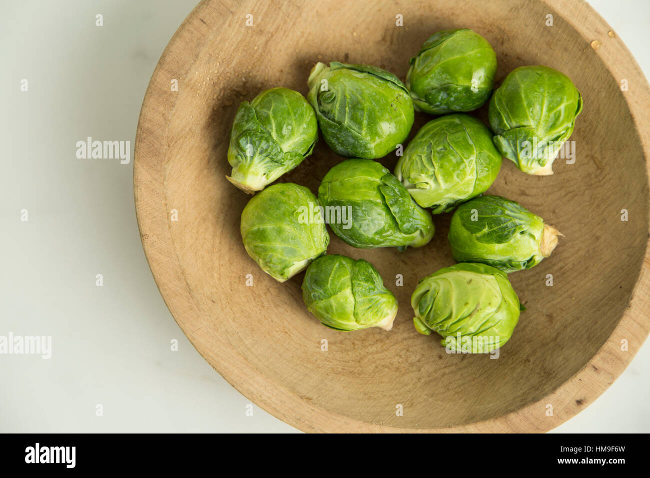 a pile of organic brussels sprouts in a wooden bowl Stock Photo