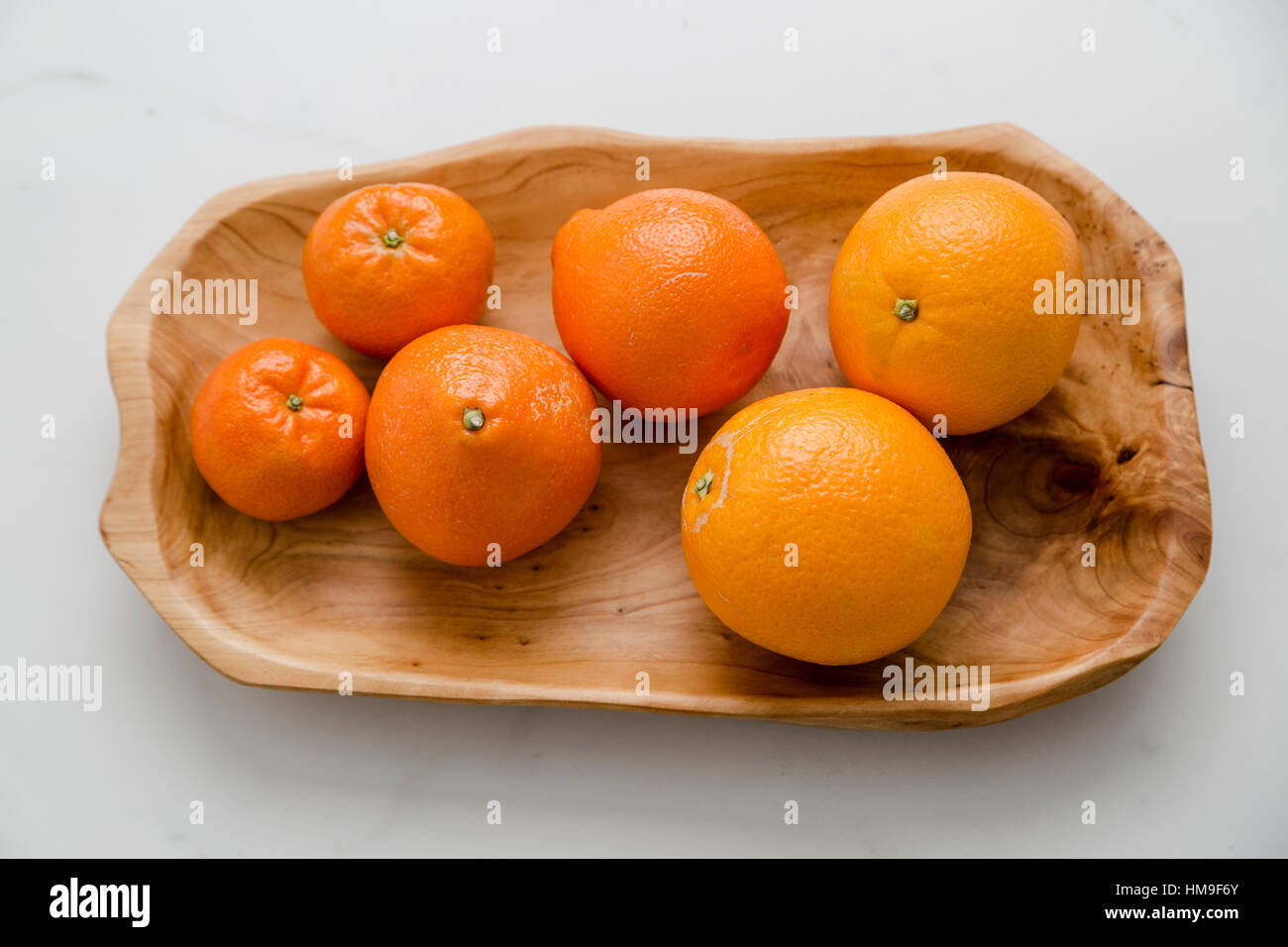 A hand carved wooden bowl with organic oranges and tangerines Stock Photo