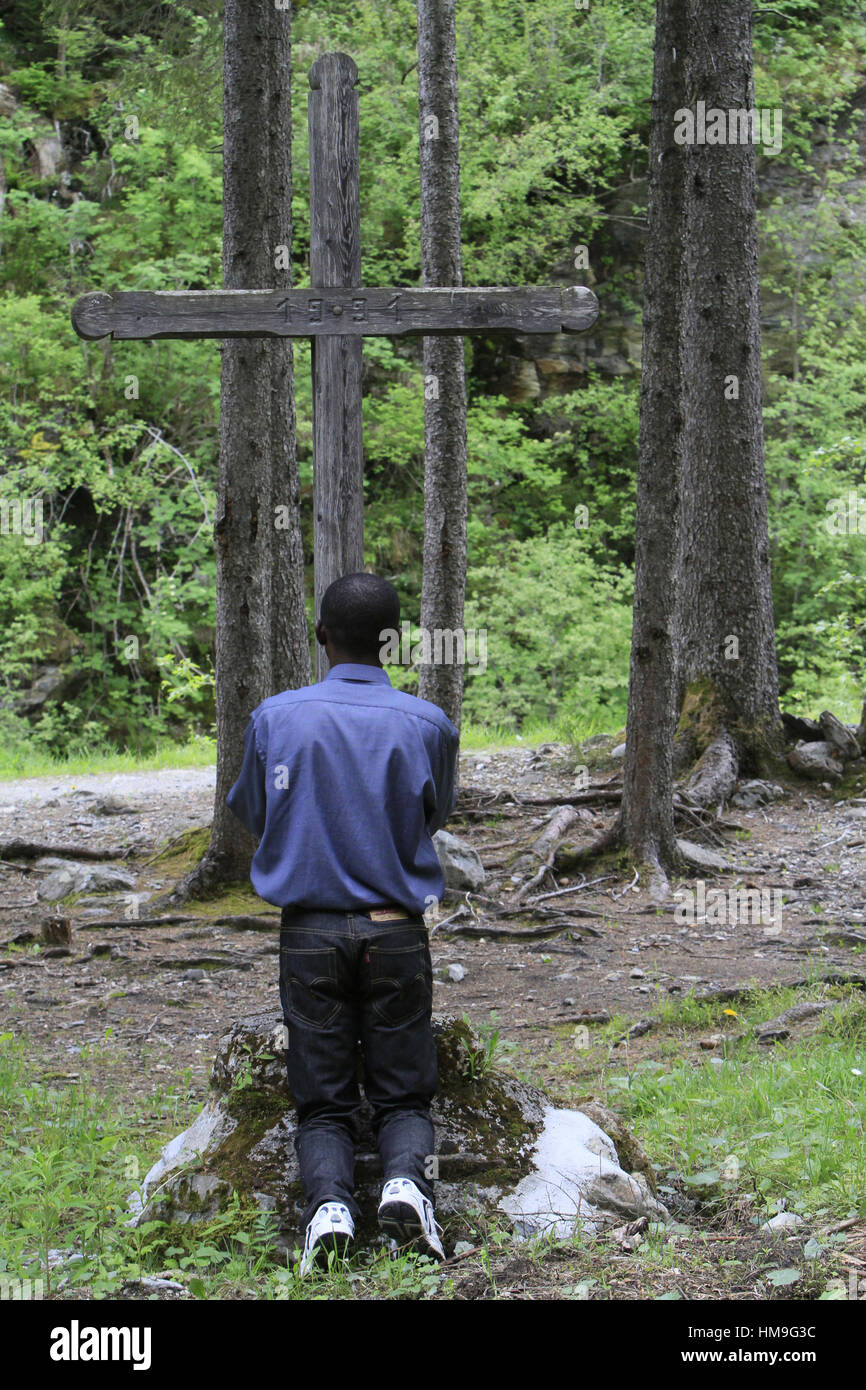 Pèlerin Africain se recueillant devant une croix. Les Contamines-Montjoie. Stock Photo