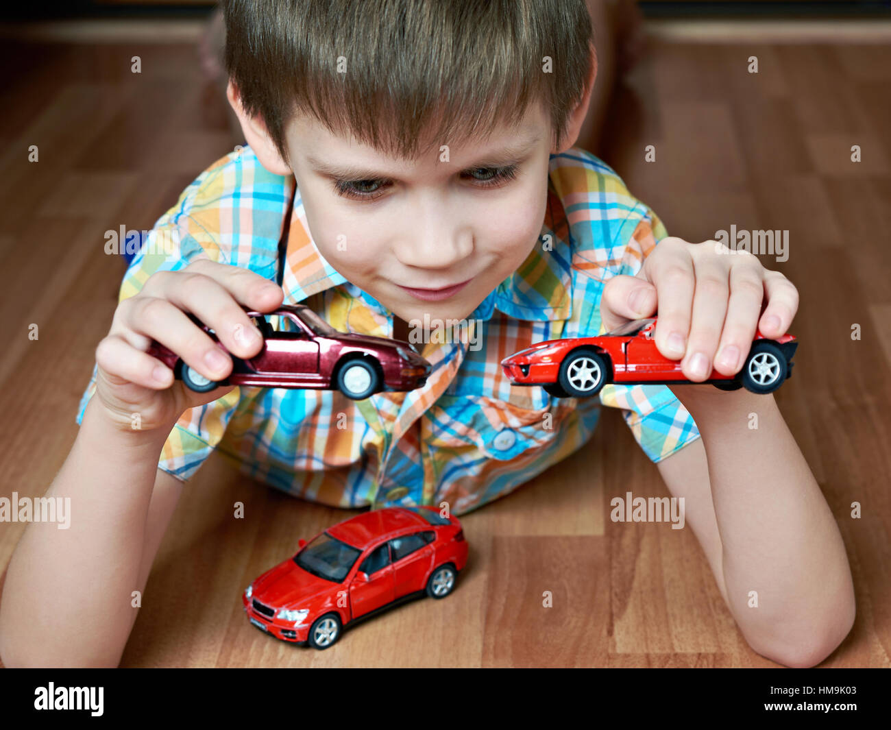 Boy playing with toy cars on wooden floor Stock Photo - Alamy