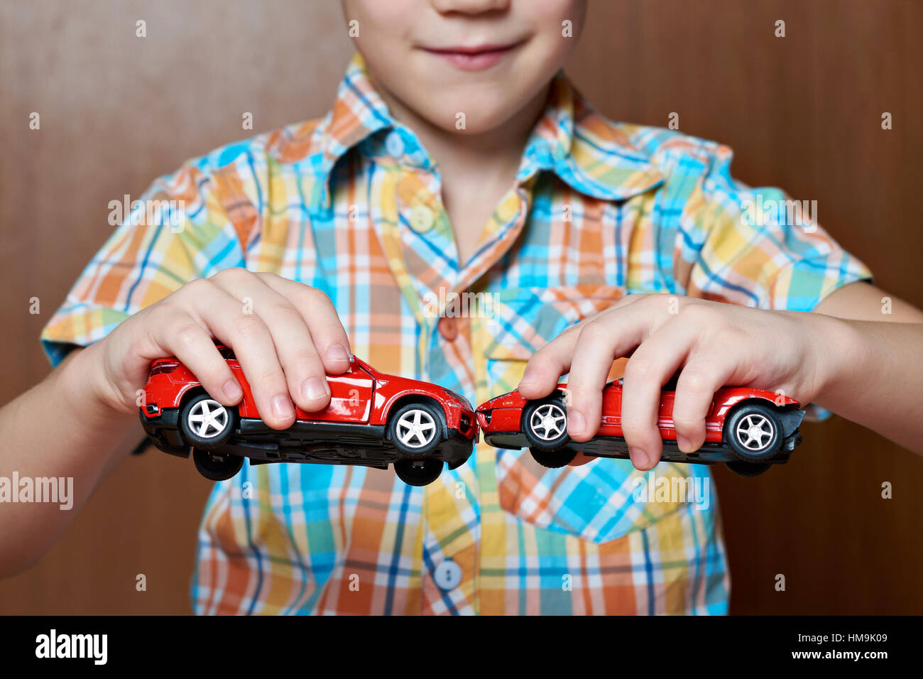 Boy playing with toy cars on wooden floor Stock Photo