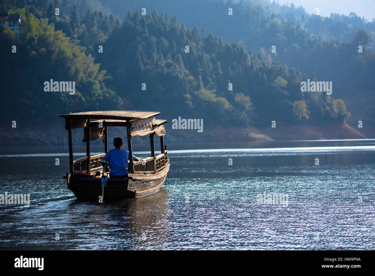 A traditional boat meanders slowly in Fengle Reservoir. Anhui Province, China Stock Photo