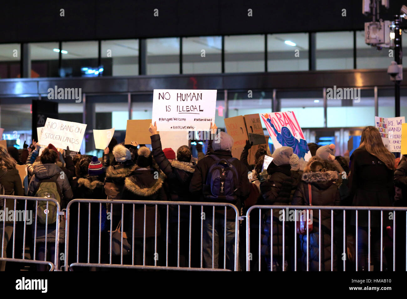 New York, USA. 1st Feb, 2017. Demonstrators protest in front of the Jacob K. Javits Federal Building under the gaze of surveillance cameras with signs including, 'No Human Being is Illegal'. They want to let Homeland Security Immigration and Customs Enforcement know that they are against Donald Trump's recent decision to ban immigrants, and Muslims from the US. February 1, 2017 Stock Photo