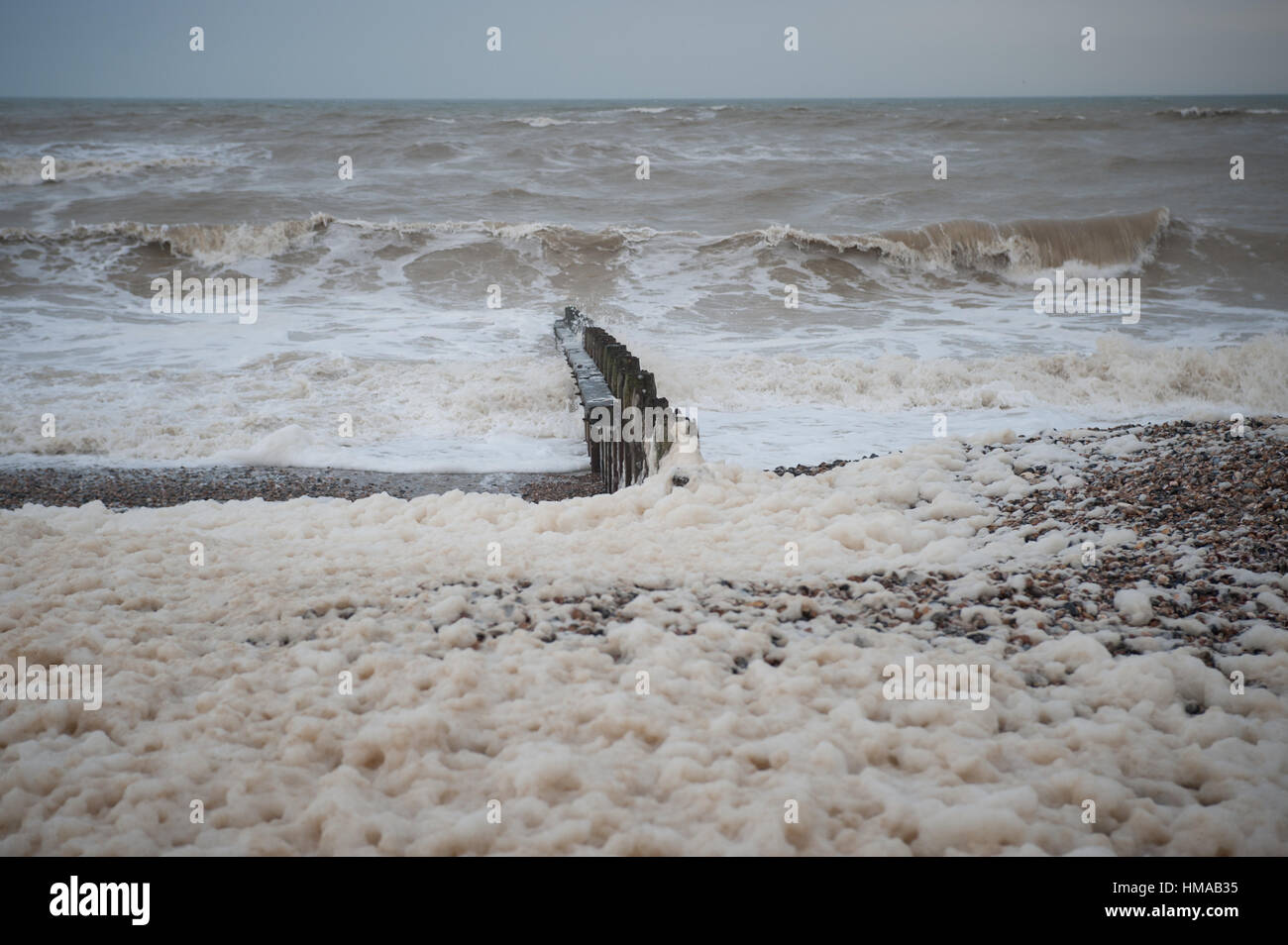 Large amounts of sea foam, caused by a recent storm, covers the beach in Littlehampton, West Sussex, UK. The sea foam is created by the agitation of seawater, particularly when it contains high concentrations of dissolved organic matter. Stock Photo