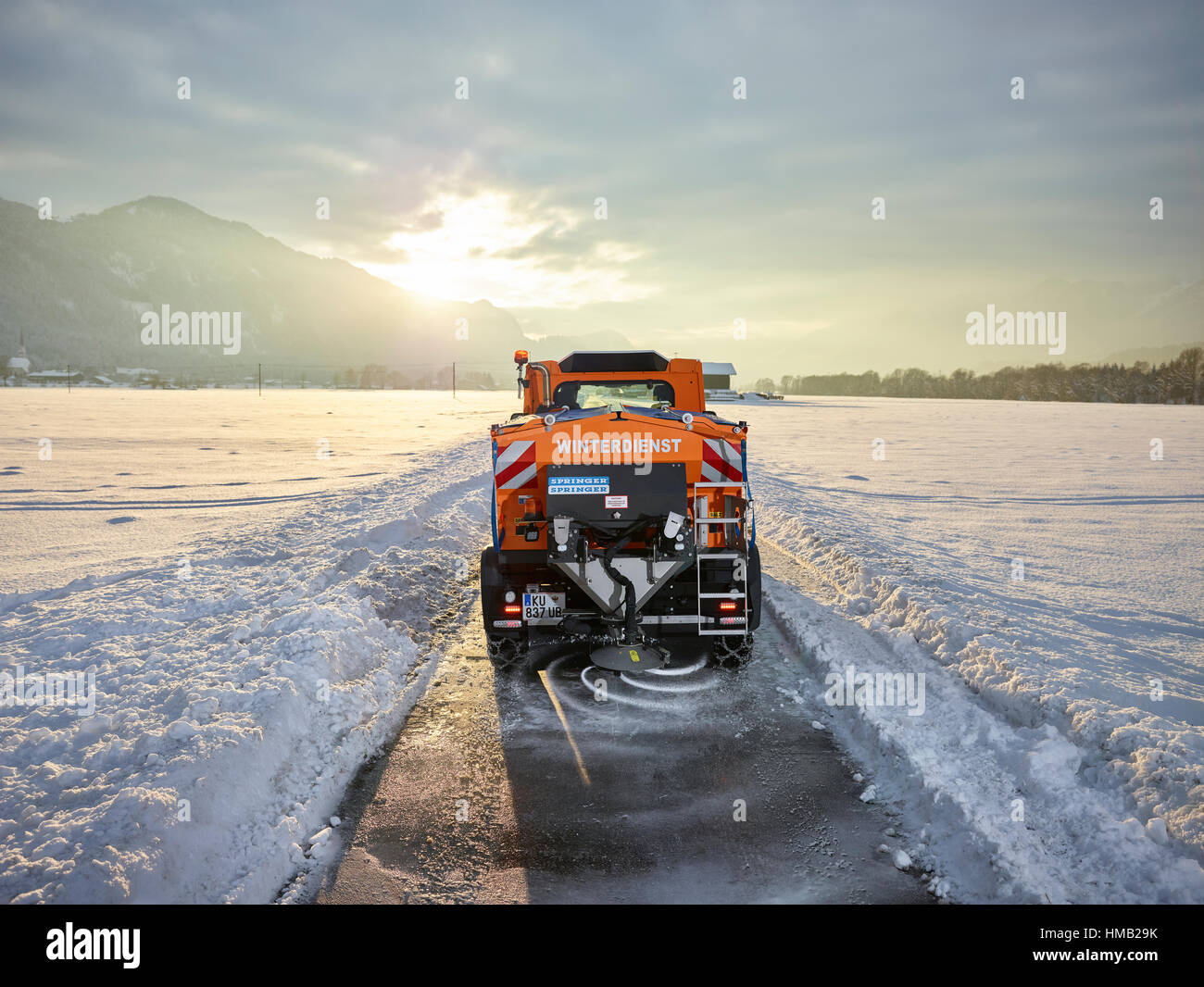 Snow plow dispenses salt on road, winter maintenance, Inntal, Tyrol, Austria Stock Photo