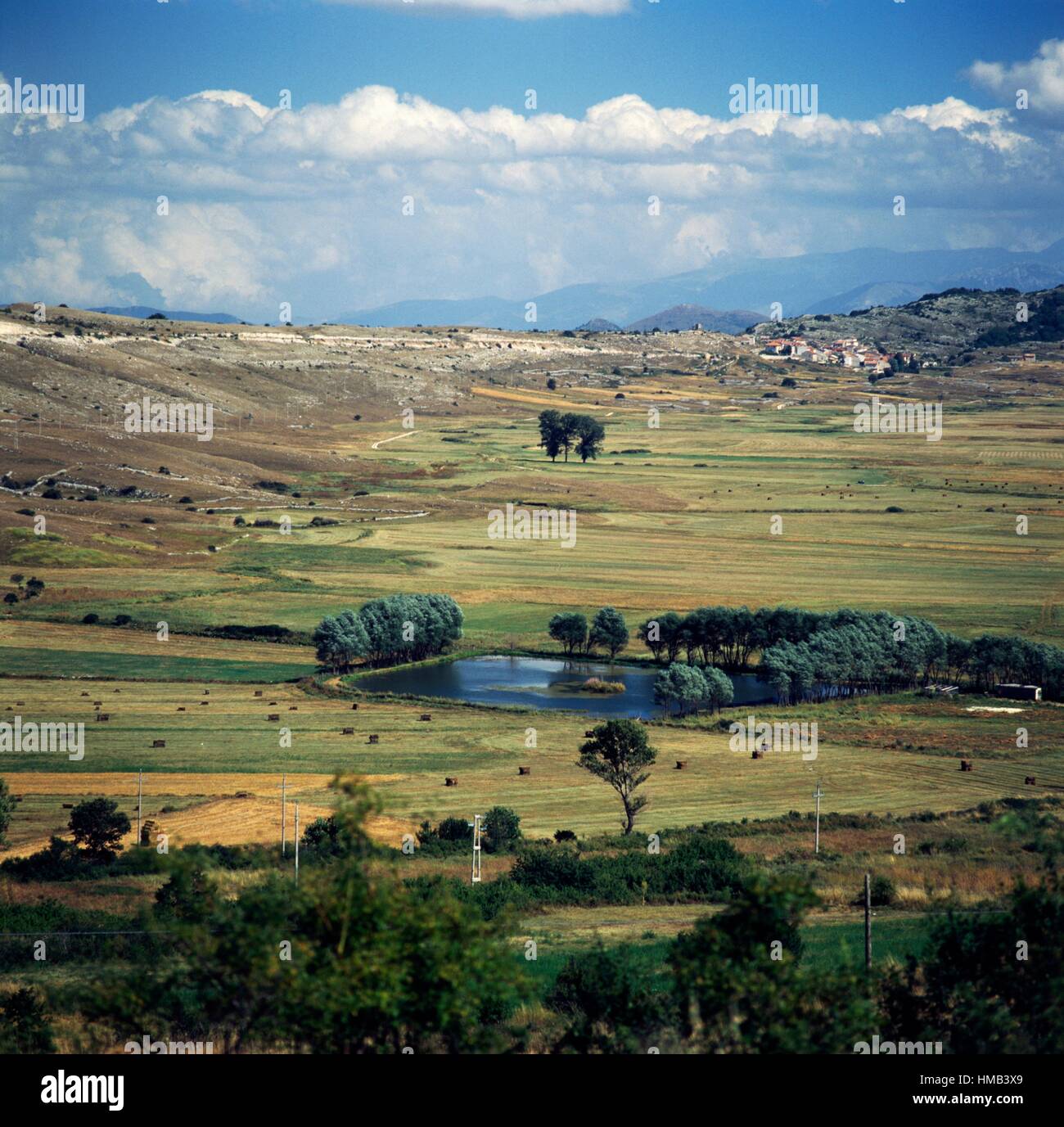 A pool of water on the Rocche plateau, with the village of Rocca di Mezzo in the background, Abruzzo, Italy. Stock Photo