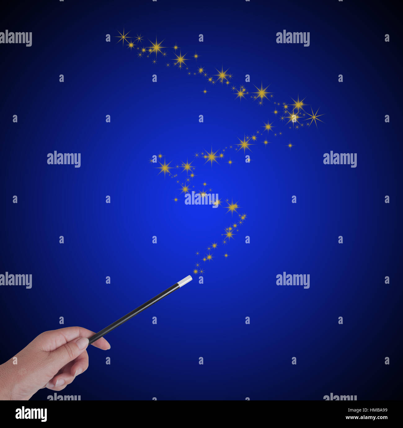 Magic wand in hand, on blue, with copyspace to make dreams come true. Stock Photo