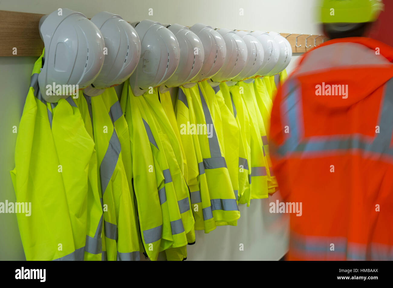 Man In safety coat walking past hangars of safety clothing Stock Photo