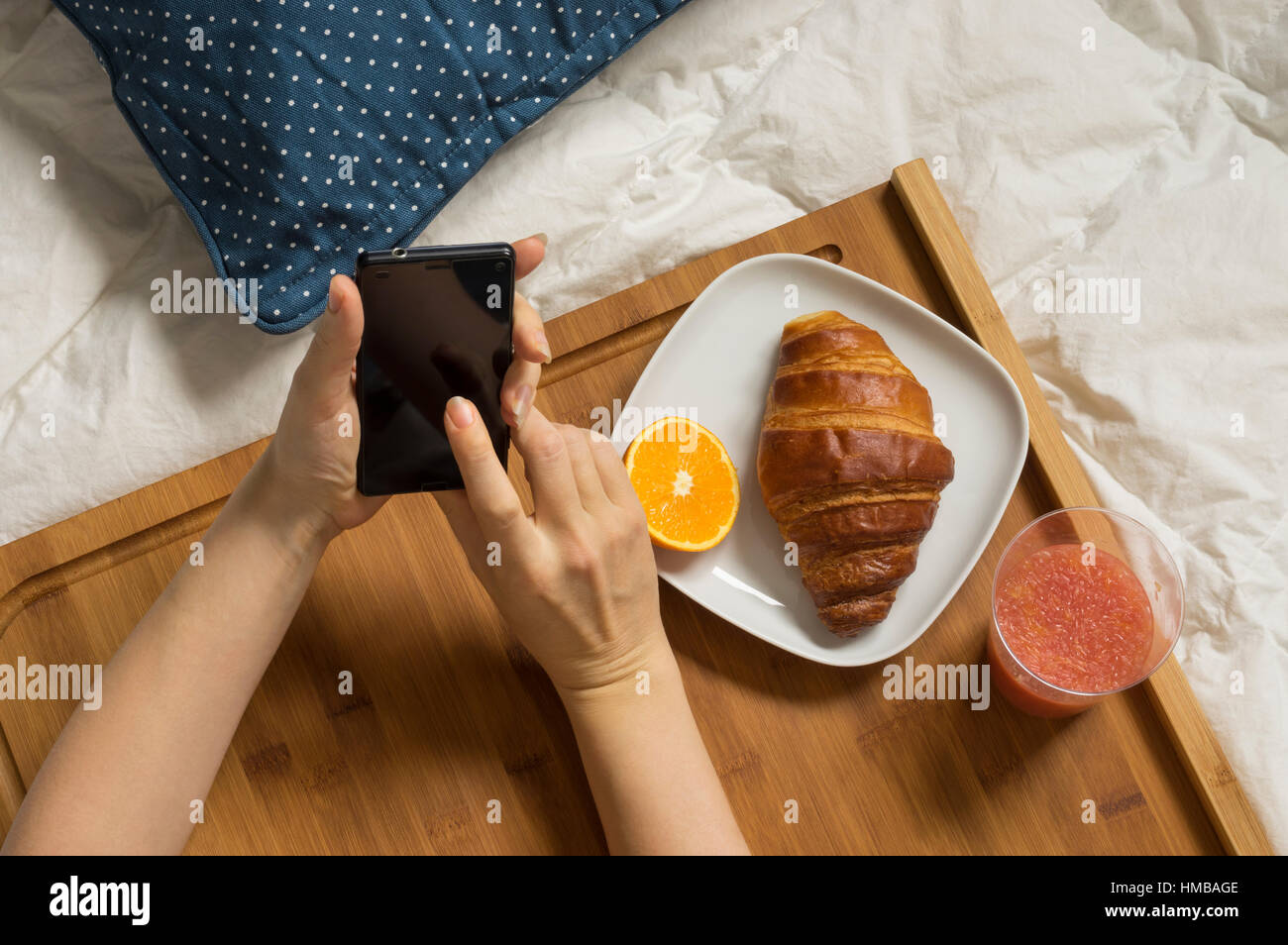 Woman hands working with mobile phone at bed and having breakfast Stock Photo