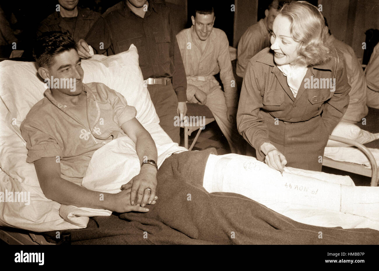 Marlene Dietrich, motion picture actress, autographs the cast on the leg of Tec 4 Earl D. McFarland of Cavider, Texas, at a United States hospital in Belgium, where she has been entertaining the GIs.  November 24, 1944. Tuttle. (Army) NARA FILE #:  111-SC-232989 WAR & CONFLICT #:  758 Stock Photo