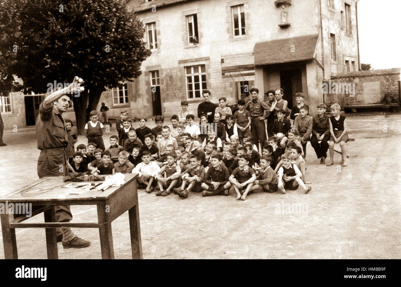 Cpl. Paul Operer, New York City, amuses a group of French children who have taken refuge at a church near Plaennec, in the Brest area, France.  His GI prestidigitations amused the children and took their minds off their troubles.  August 20, 1944. Hall. (Army) Exact Date Shot Unknown NARA FILE #:  111-SC-193132 WAR & CONFLICT BOOK #:  1257 Stock Photo