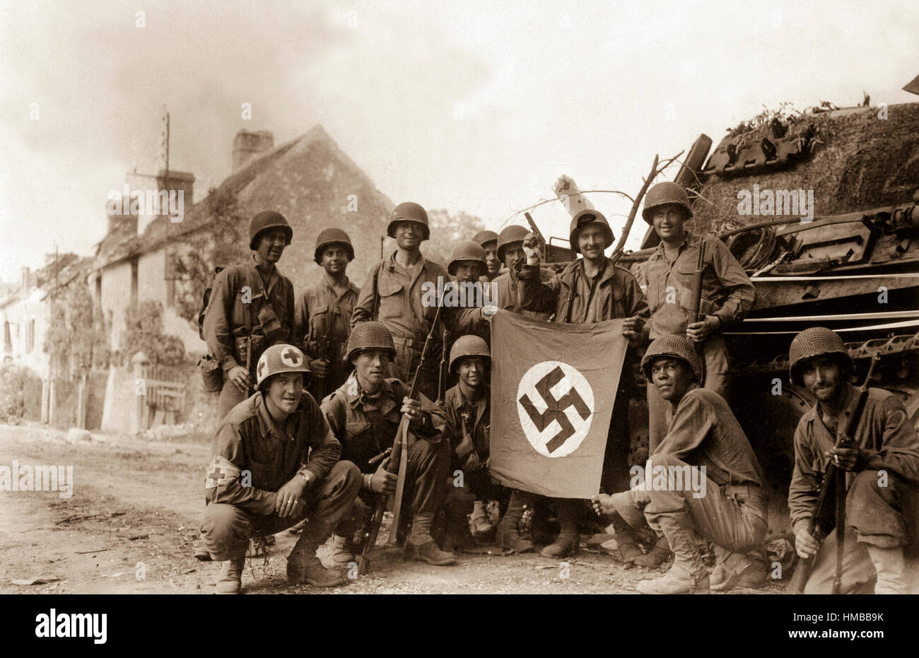 Lined up in front of a wrecked German tank and displaying a captured swastika, is group of Yank infantrymen who were left behind to 'mop-up' in Chambois, France, last stronghold of the Nazis in the Falaise Gap area.  August 20, 1944. Tomko.  (Army Surgeon General) Stock Photo