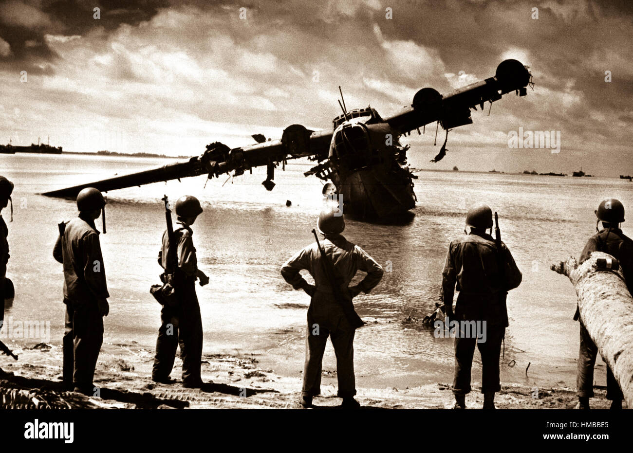 U.S. Army troops pause for a look at a Japanese seaplane during the battle of Makin.  The plane was under repair in the lagoon when the invasion started.  The Japanese used it as a machine gun nest until American fliers took care of it.  November 1943.  (Coast Guard) Exact Date Shot Unknown NARA FILE #:  026-G-3000 WAR & CONFLICT BOOK #:  1320 Stock Photo