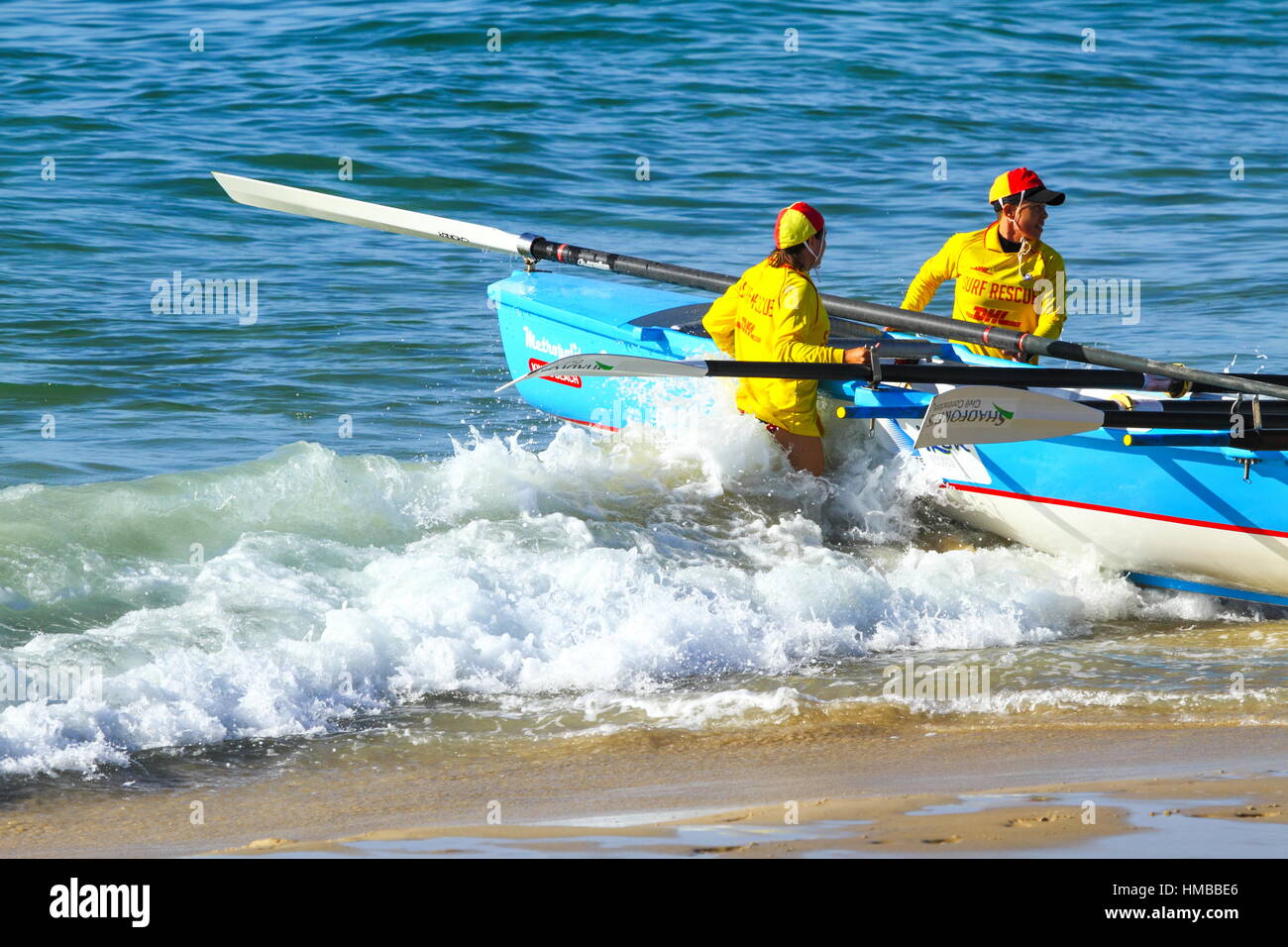 Two Surf Lifesavers launching a surf boat for some training at Kings Beach on the Sunshine Coast of Queensland, Australia. Stock Photo
