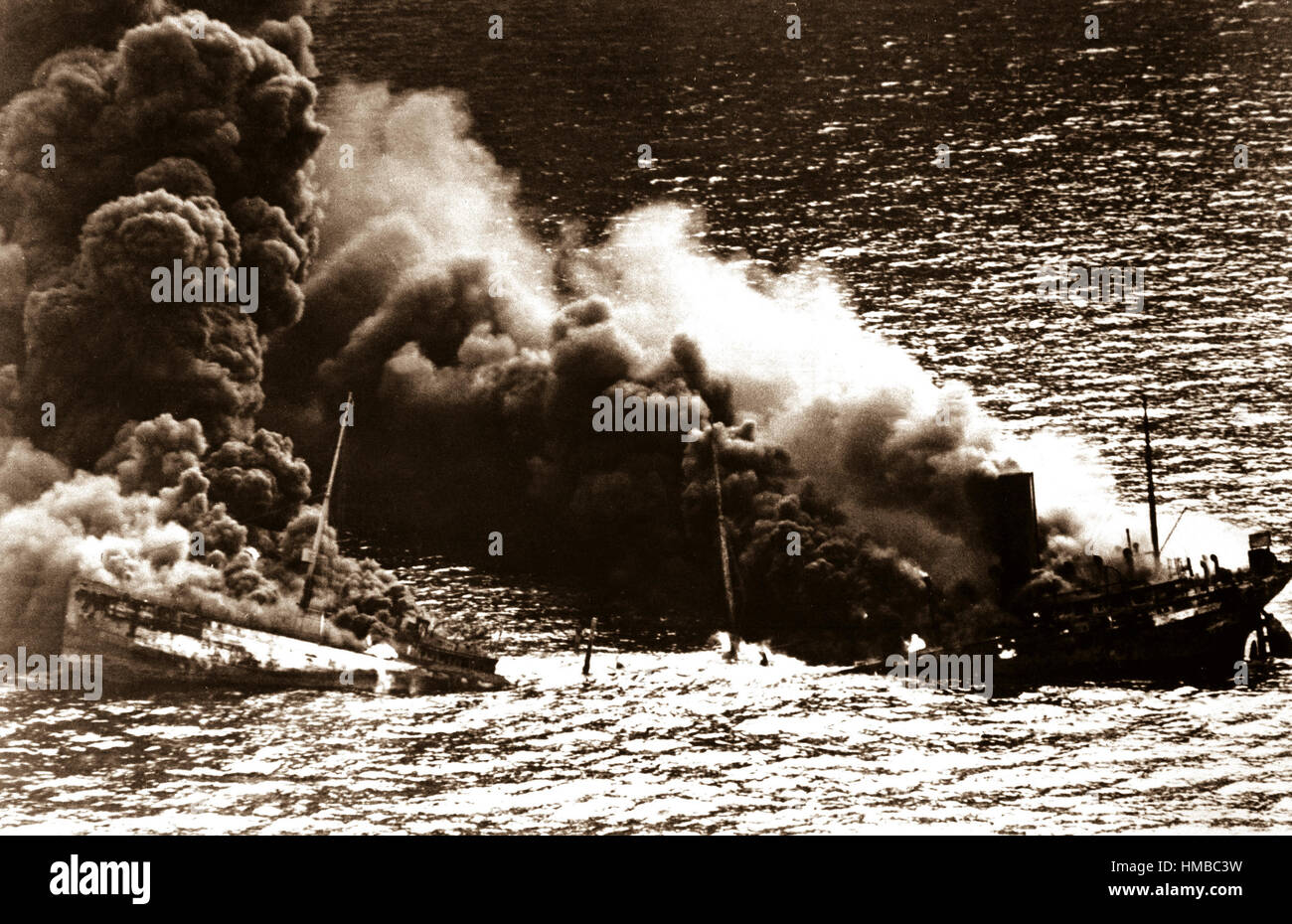 Allied tanker torpedoed in Atlantic Ocean by German submarine.  Ship crumbling amidship under heat of fire, settles toward bottom of ocean.  1942.  (Navy) Stock Photo