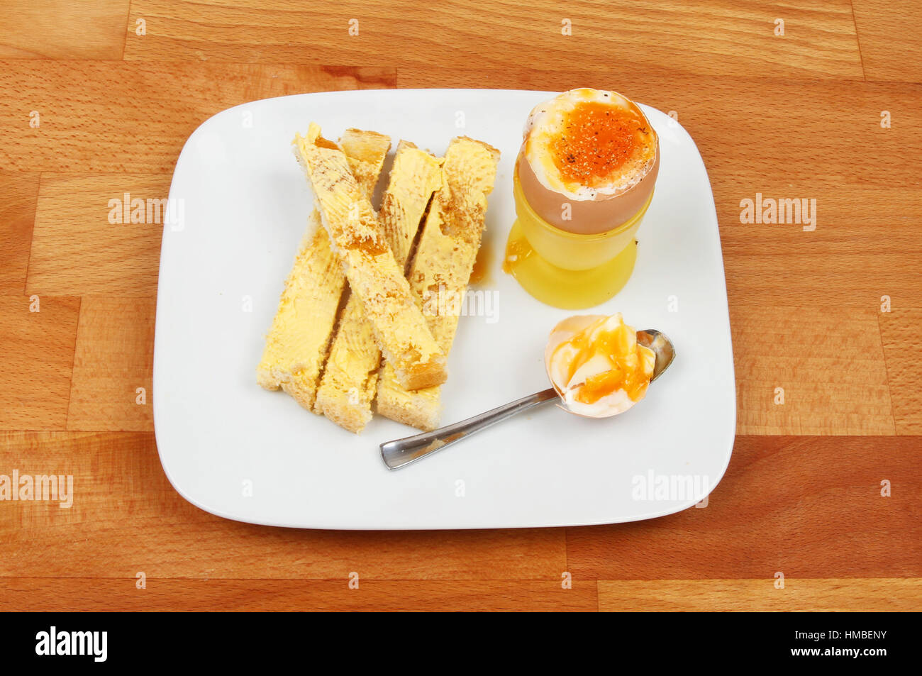 Soft boiled egg and toast on a plate on a wooden kitchen worktop Stock Photo