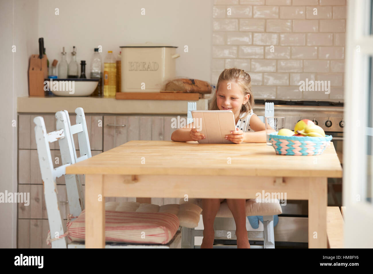 Young Girl At Home Using Digital Tablet On Kitchen Table Stock Photo ...