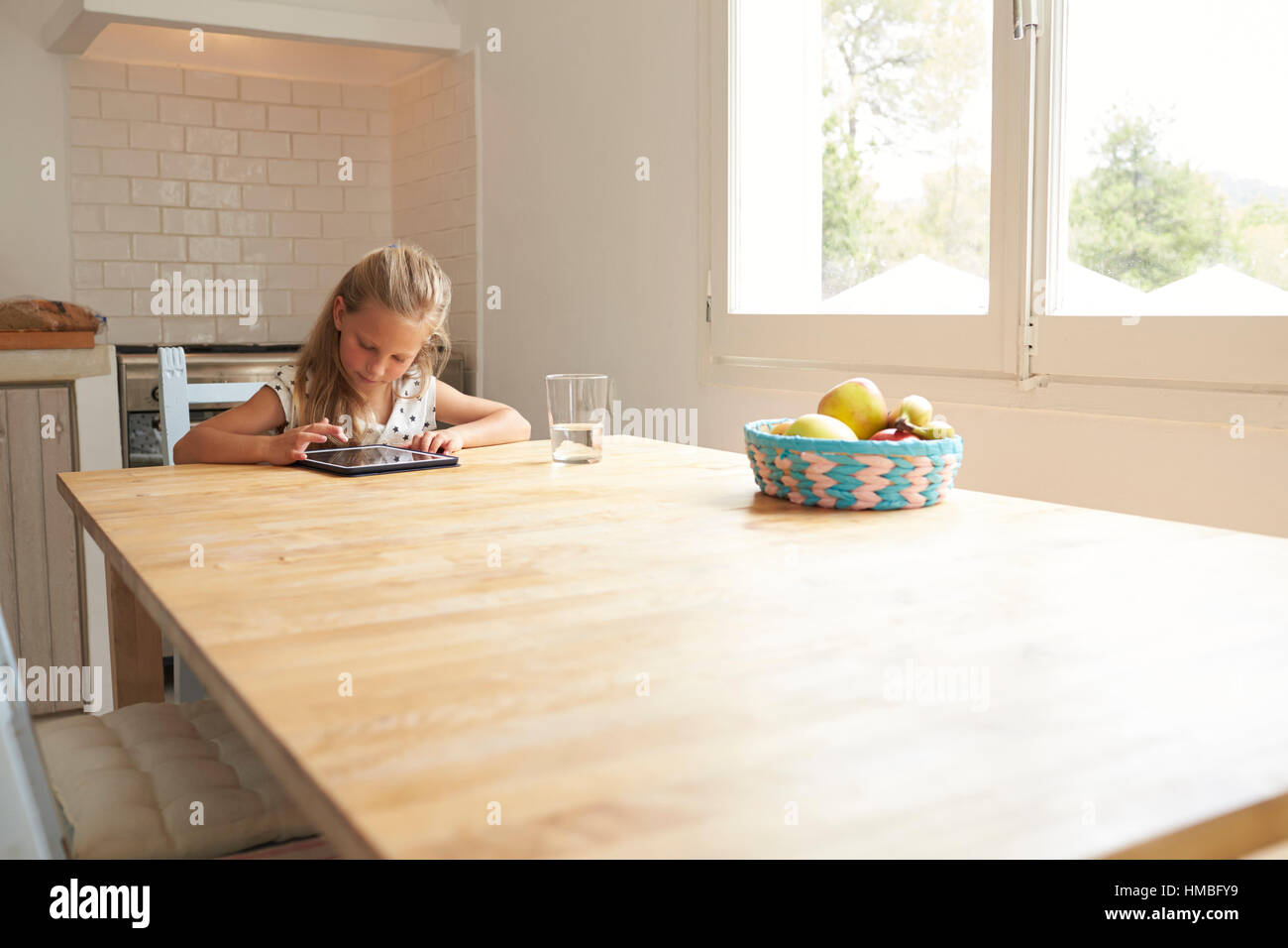Young Girl At Home Using Digital Tablet On Kitchen Table Stock Photo ...