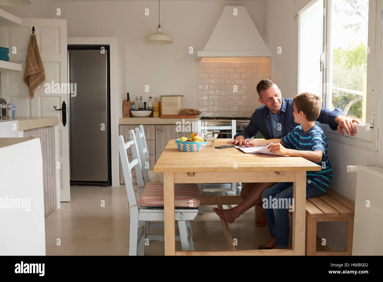 Father Helping Son With Homework Sitting At Kitchen Table Stock Photo ...