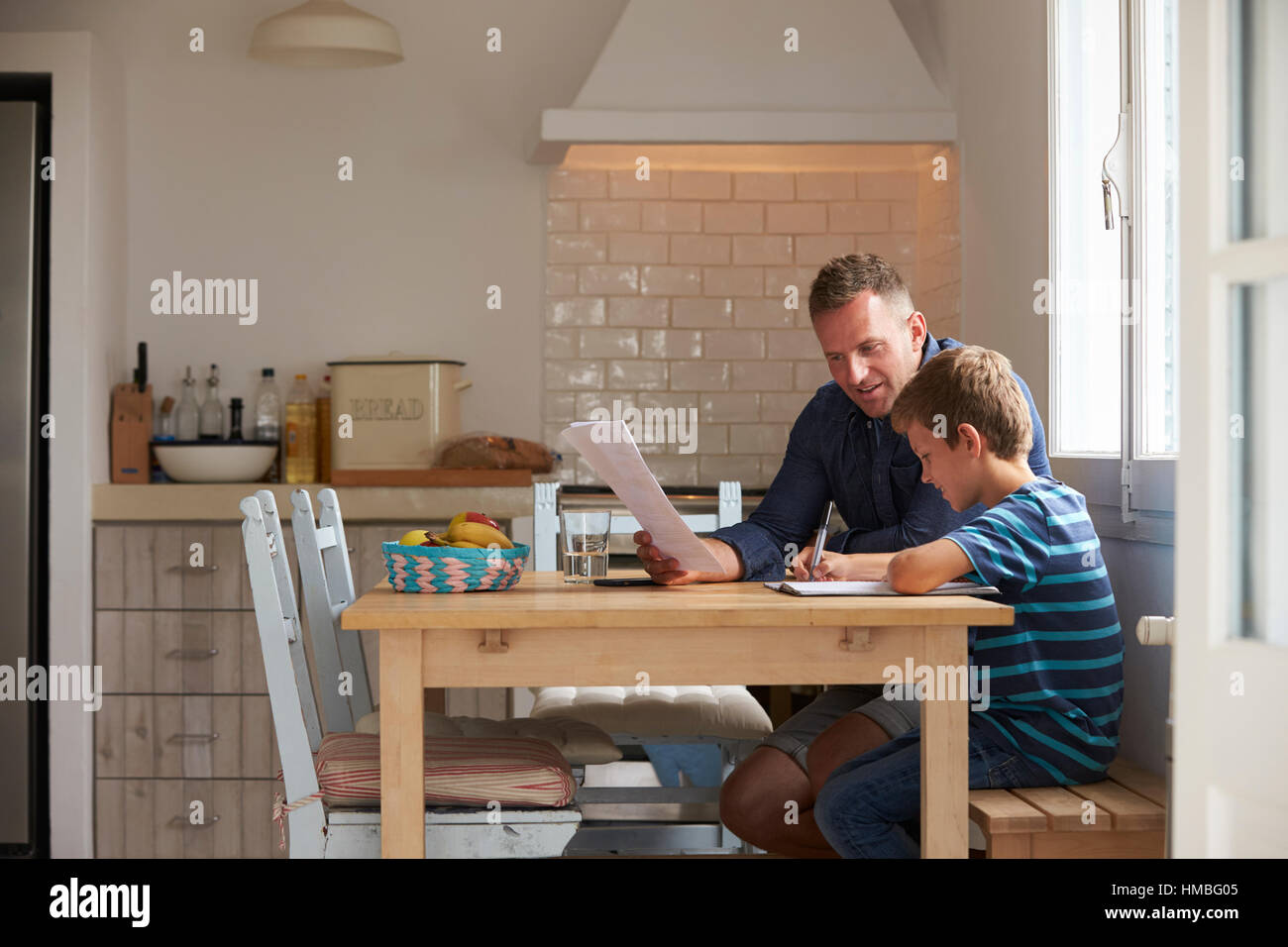 Father Helping Son With Homework Sitting At Kitchen Table Stock Photo ...