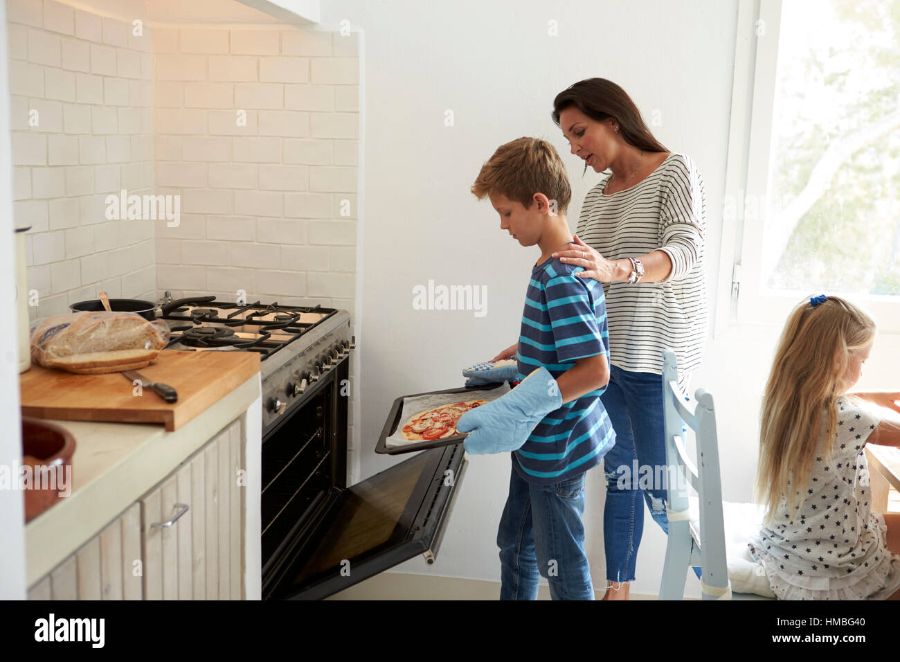 Mother And Children Baking Homemade Pizza In Oven Stock Photo