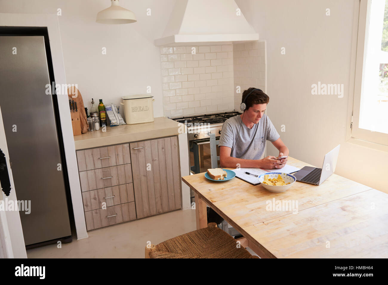Teenage boy wearing headphones using technology in a kitchen Stock Photo Alamy