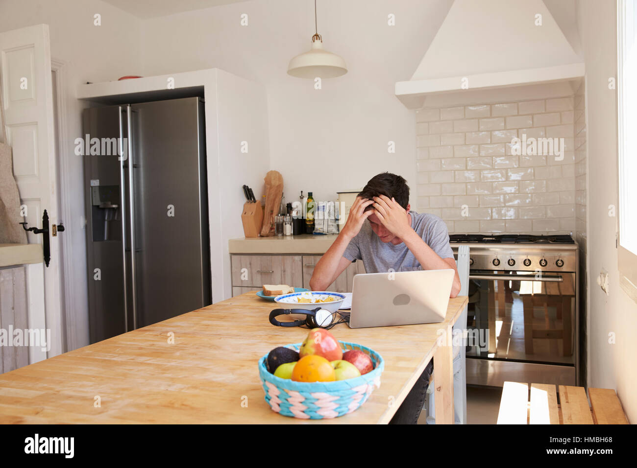 Stressed teenage boy studying with computer in kitchen Stock Photo - Alamy
